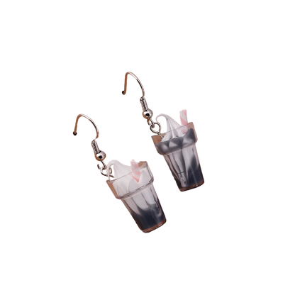 Dangle earrings resembling milkshakes on a wooden stand with 'Love Jewels' engraving.