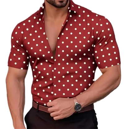 Man wearing a red shirt with white polka dots, posing against a blurred background
