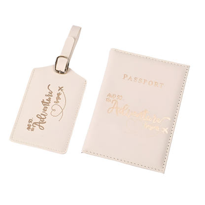 A passport holder and luggage tag set with the phrase "And so the adventure begins" in elegant script. The design is sleek and stylish, perfect for travel.