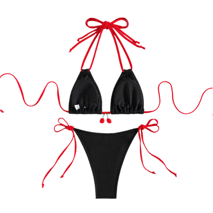 A black bikini with red string ties and cherry embellishments on the top. The design is simple yet charming, with a touch of whimsy.
