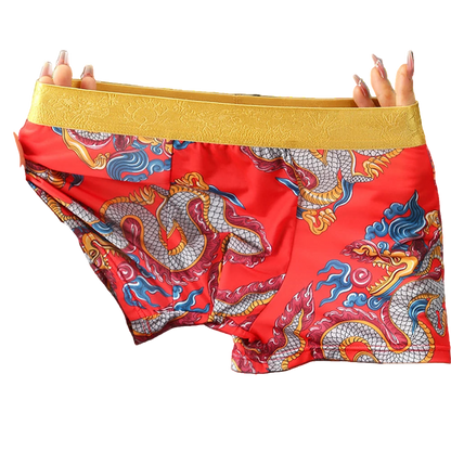 Red boxer briefs with dragon design held by a person against a gray background