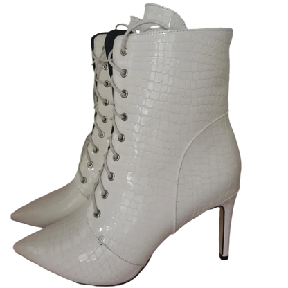 White lace-up high-heeled boots on a light pink surface with a white background