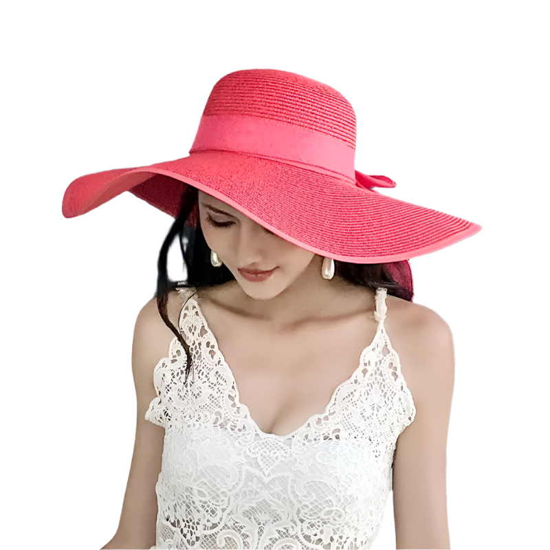 Woman wearing a large pink sun hat in front of a vintage vehicle.