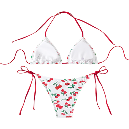 A white bikini with a cherry print. It features a classic triangle top and tie-side bottoms with red strings, giving it a playful and fruity look.
