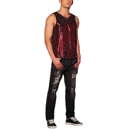 A man wearing a sleeveless sequined top with a red-to-purple gradient and black distressed jeans, standing in front of a purple tinsel curtain backdrop.