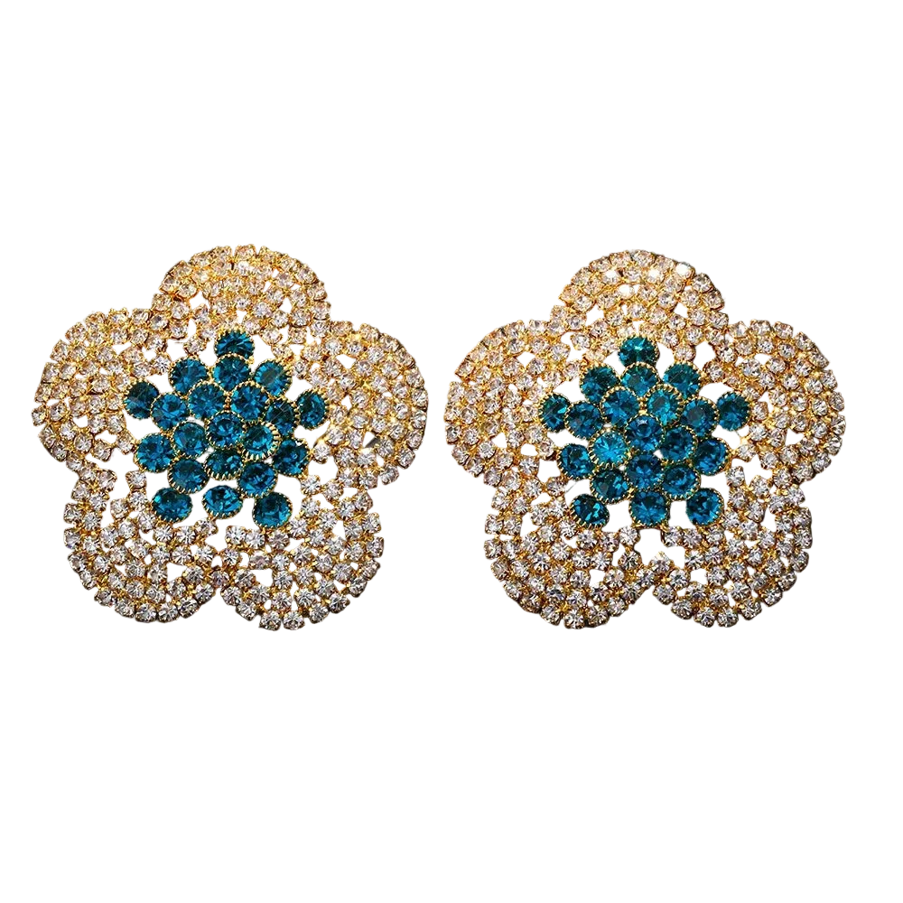 Pair of ornate earrings with blue center and gold and diamond-like border on black background