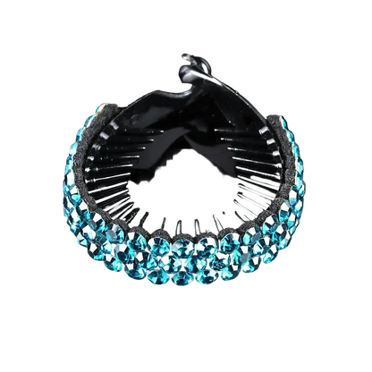 A black hair claw clip embellished with a row of faceted light blue rhinestones on the front, shown on a reflective black background.