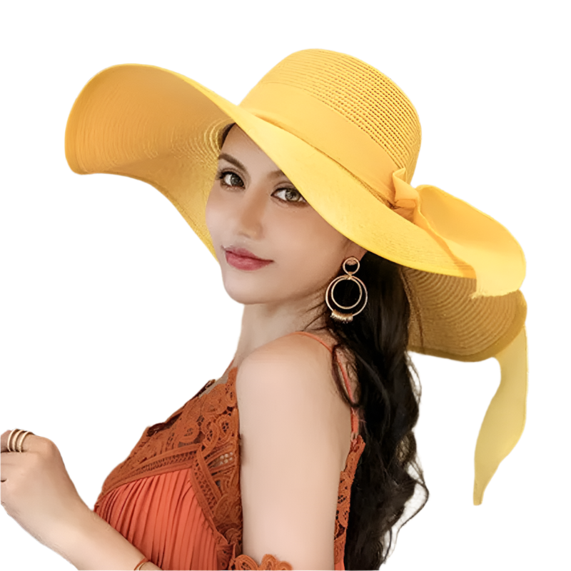 Woman wearing a yellow hat with a large bow indoors.