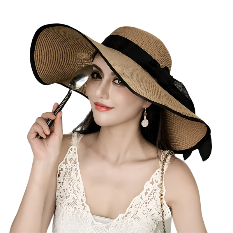 Woman wearing a large straw hat with a black ribbon, sitting in an outdoor setting.
