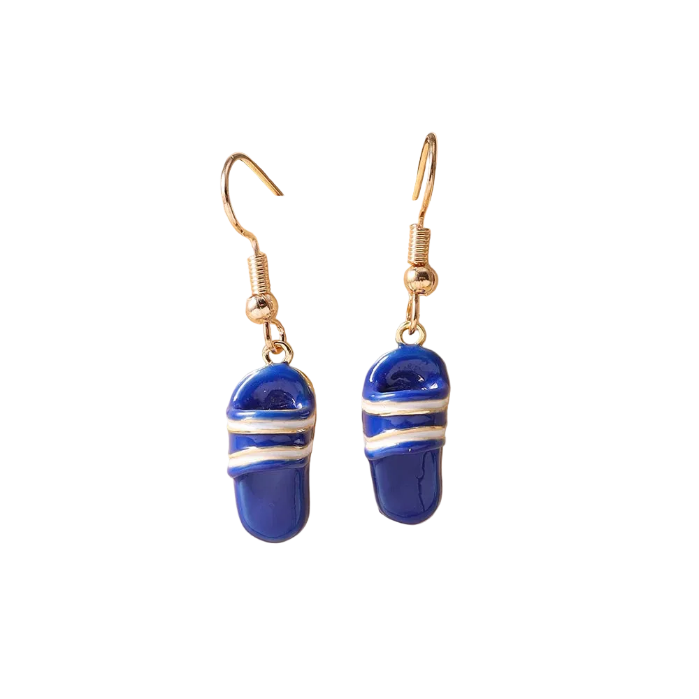 A pair of dangling earrings with blue slipper-shaped charms wrapped in white stripes, hanging from gold-tone hooks on a beige ceramic display stand.