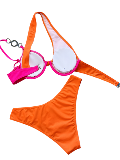 A two-tone bikini with orange and pink sections, featuring asymmetrical straps and jeweled embellishments. The design is vibrant and unique, perfect for a standout beach look.