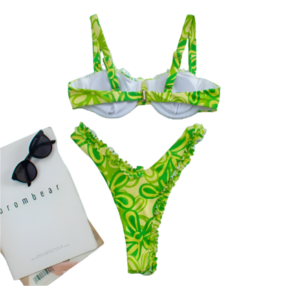 A vibrant bikini set with a green floral pattern and pink ruffle trim. The top has structured cups and adjustable straps, while the bottom features a high-cut design.