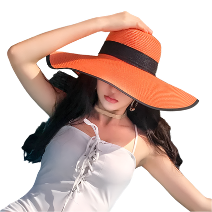 Woman wearing an orange hat with a black band, sitting on a chair outdoors.