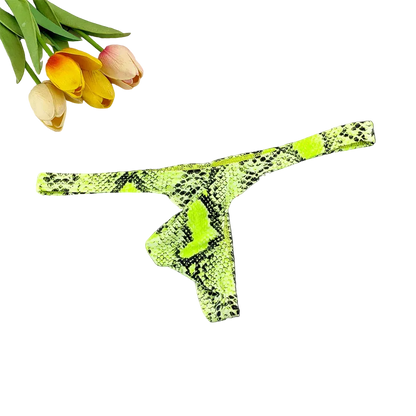 A neon green and black snakeskin-print thong laid flat on a dark surface, with tulips and a white grid tile as styled props.