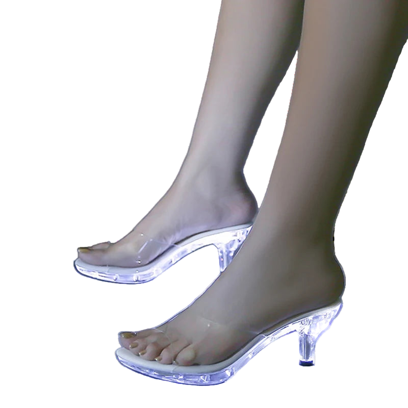 Clear high-heeled shoes with LED lights on a reflective surface