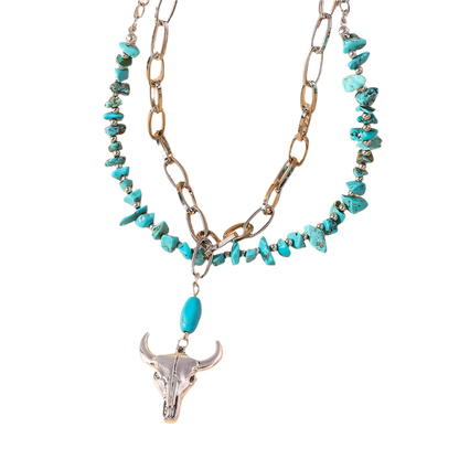 Necklace with turquoise beads and a bull head pendant on a beige background