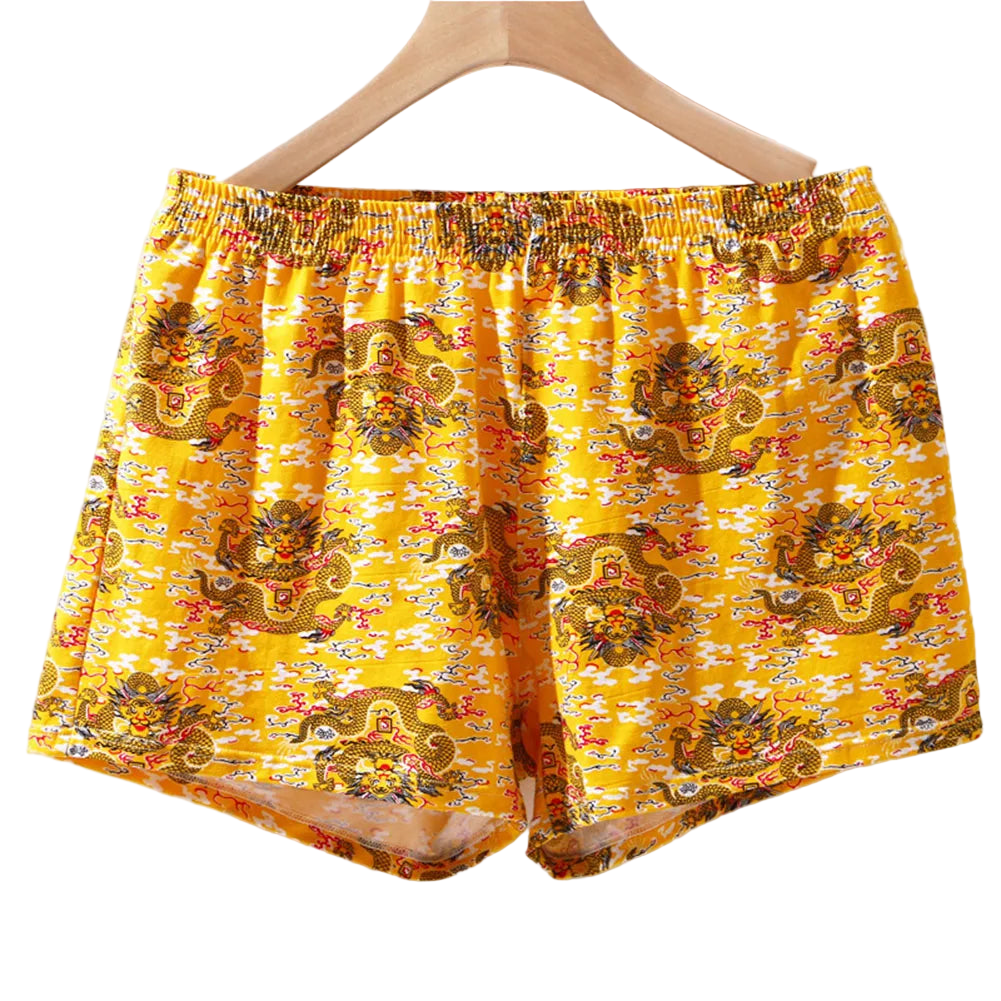 Yellow boxer shorts with dragon pattern on a hanger against a white background