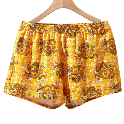 Yellow boxer shorts with dragon pattern on a hanger against a white background