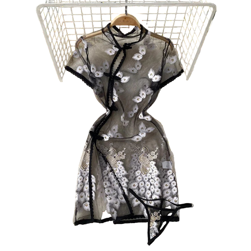 Black embroidered dress on a hanger with white flowers and a hat in the background