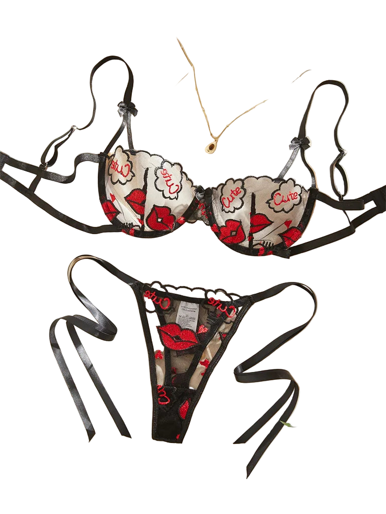 Black lingerie set with red floral and lip designs on a beige fabric background.