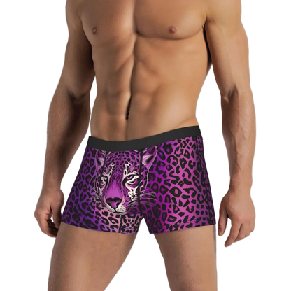 A man wearing men's boxer briefs with a purple and black leopard print and a realistic purple tiger face graphic on the front, set against a white paneled wall.