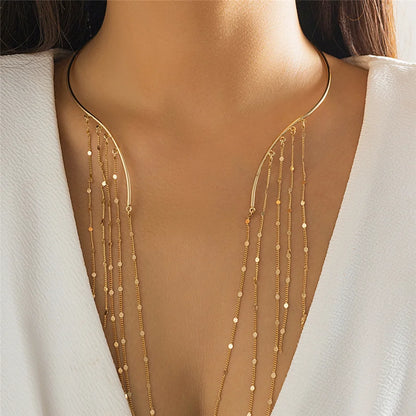 Gold necklace with dangling beads on a model wearing a white top