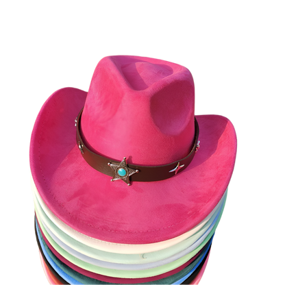 Stack of colorful cowboy hats with a pink top on grass