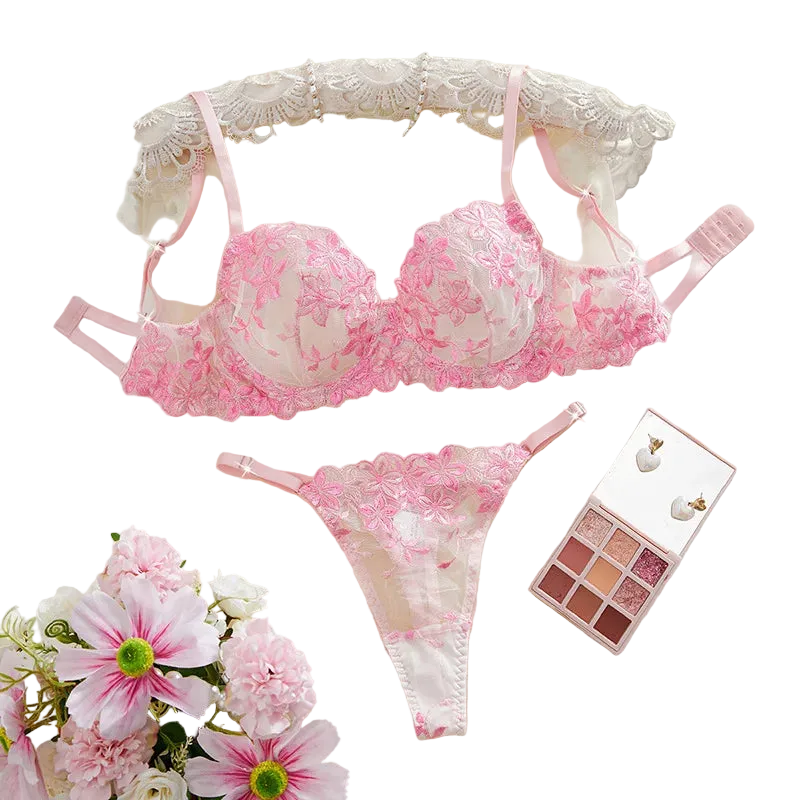 Pink lace lingerie set with flowers and makeup palette on a white surface