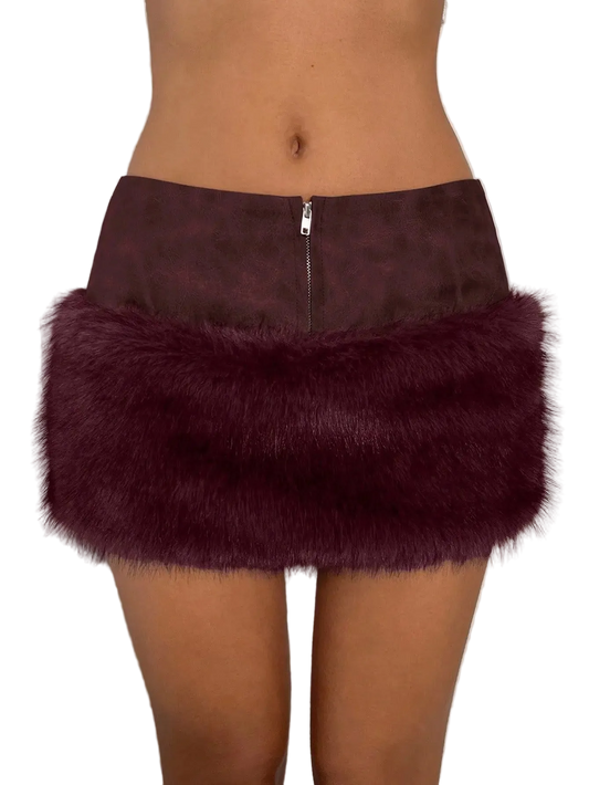 A close-up of a person wearing a mini skirt with a dark brown faux-leather top half and a fluffy deep burgundy faux-fur bottom half, shown against a plain light background.