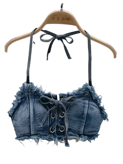Denim-style crop top with lace-up details on a hanger against a textured background.