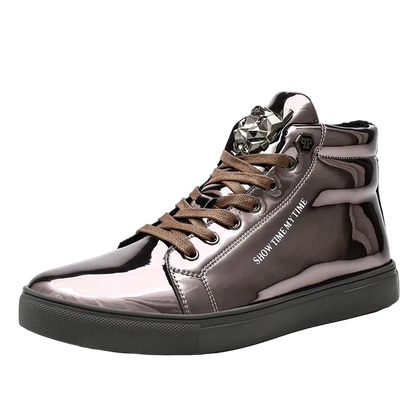 A high-top sneaker with a glossy metallic taupe-brown finish, brown laces, a black sole, and a silver rhinestone embellishment on the tongue, shown against a plain white background.