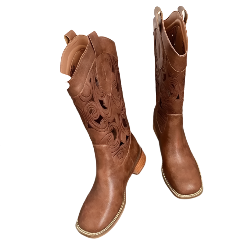 Brown cowboy boots with intricate designs on a wooden surface.