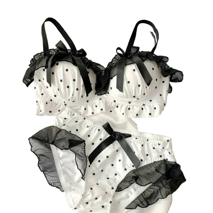White polka dot lingerie set with black accents on a white surface.