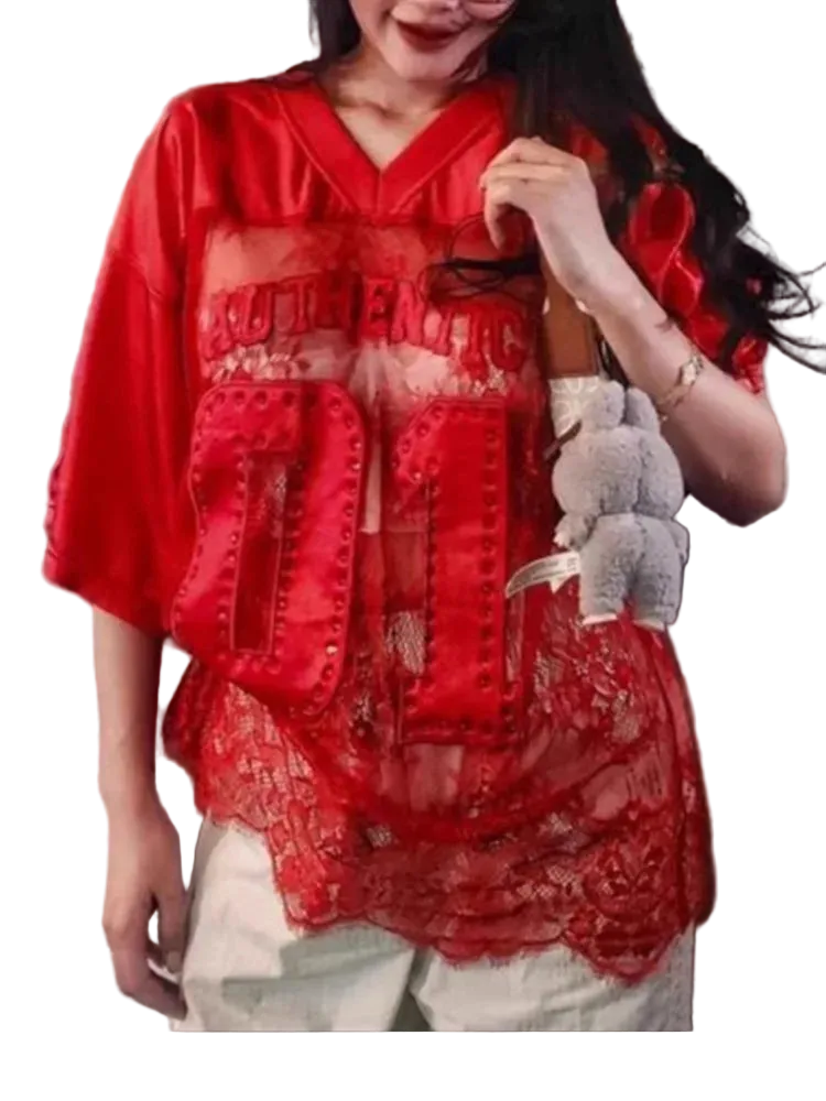 Person wearing a red lace top with text, holding a small bag.