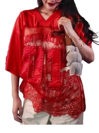 Person wearing a red lace top with text, holding a small bag.