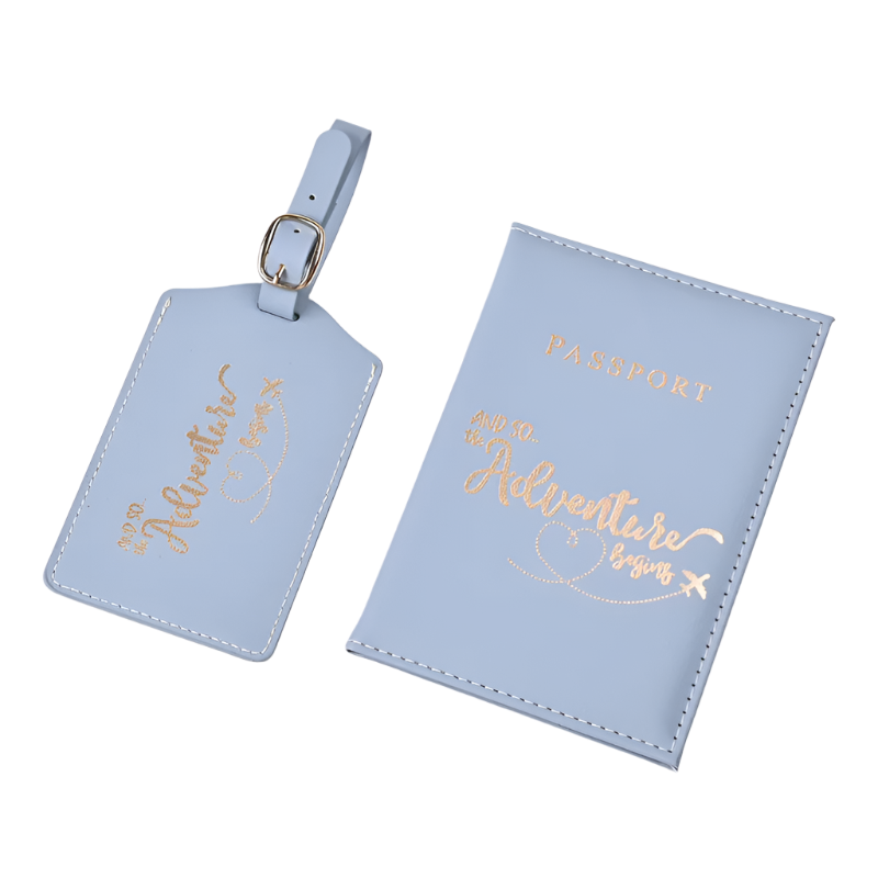 A passport holder and luggage tag set with the phrase "And so the adventure begins" in elegant script. The design is sleek and stylish, perfect for travel.