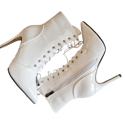 White high-heeled shoes with lace-up design on a dark surface