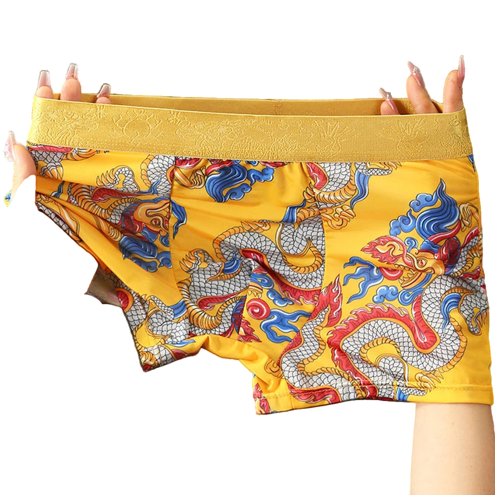 Yellow boxer briefs with dragon design held by hands on a gray background