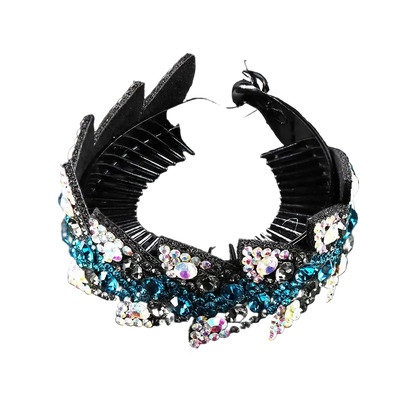 A black plastic claw-style hair comb embellished with blue, white, and iridescent rhinestones, displayed on a reflective black background.