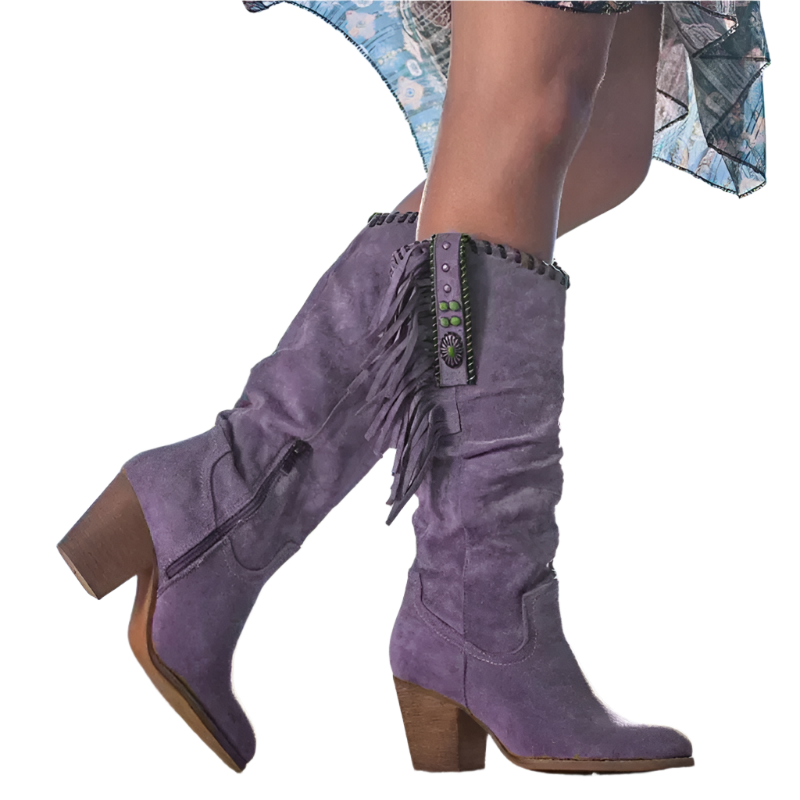 Purple suede boots with fringe details on a blurred outdoor background