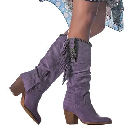 Purple suede boots with fringe details on a blurred outdoor background