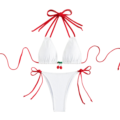 A white bikini with red string ties and cherry embellishments on the top. The design is simple yet charming, with a touch of whimsy.
