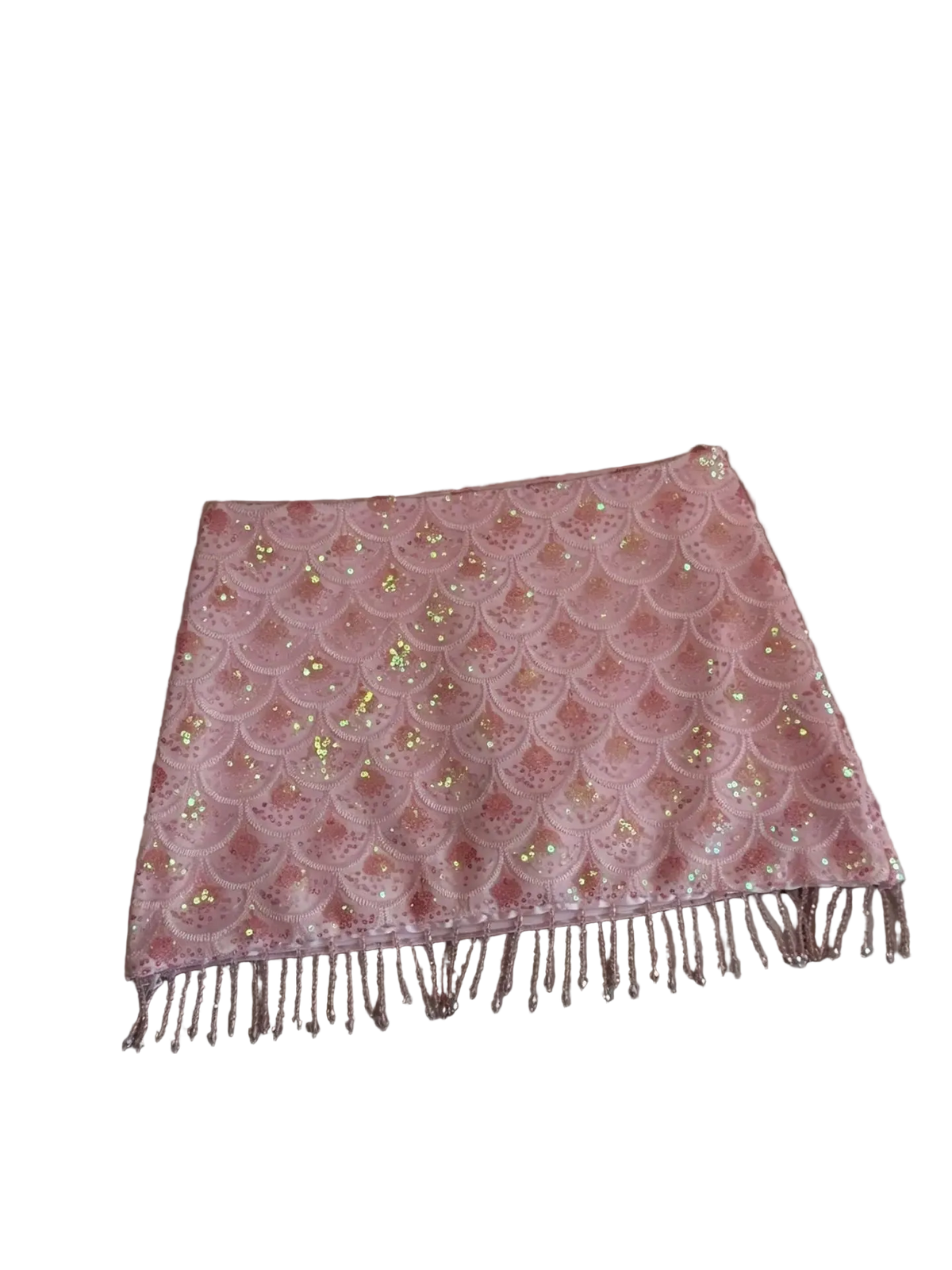 A pink sequined scarf with a scalloped lace pattern and fringe, laid flat on a beige leather sofa.