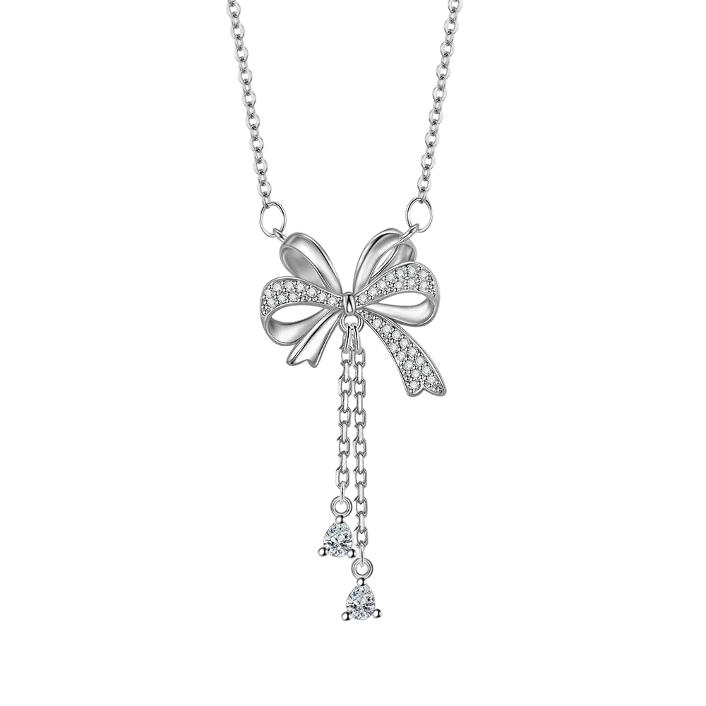 A silver bow pendant necklace adorned with small clear crystals, featuring a delicate chain and two dangling crystal charms, shown on a plain white background.