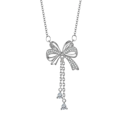 A silver bow pendant necklace adorned with small clear crystals, featuring a delicate chain and two dangling crystal charms, shown on a plain white background.