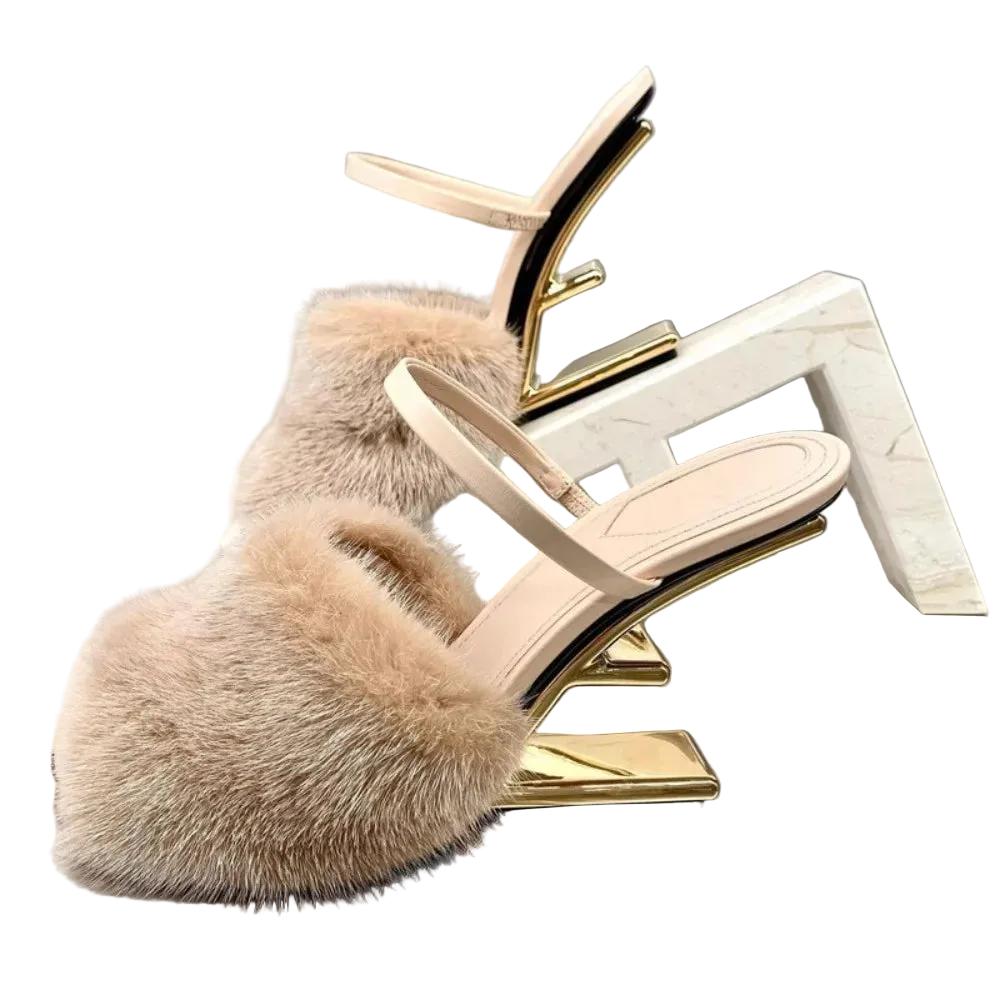 Beige fur slide sandal with gold heel on a reflective surface