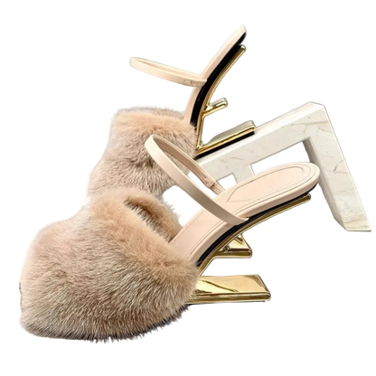 Beige fur slide sandal with gold heel on a reflective surface