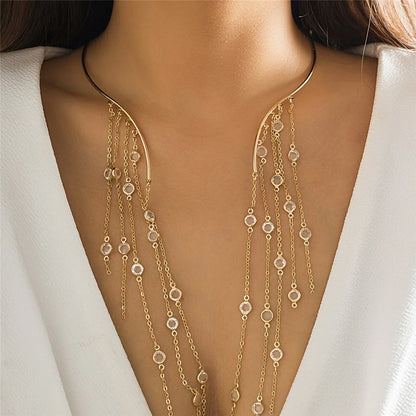 Gold necklace with dangling beads on a person wearing a white outfit